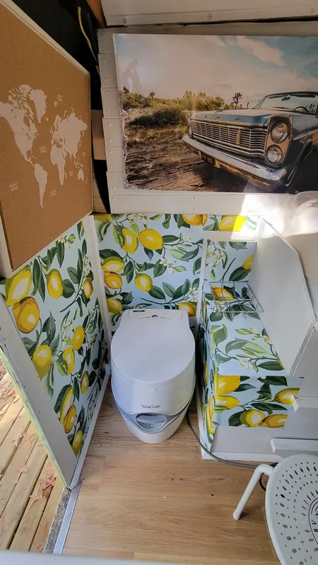 Lemon-print powder room with a portable toilet inside the Camp Calypso skoolie