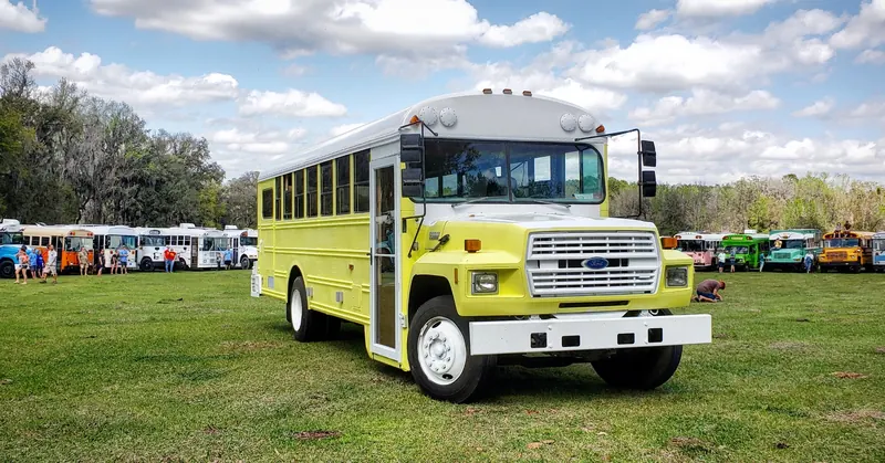 Camp Calypso, a yellow and white converted Ford school bus parked on a grass field