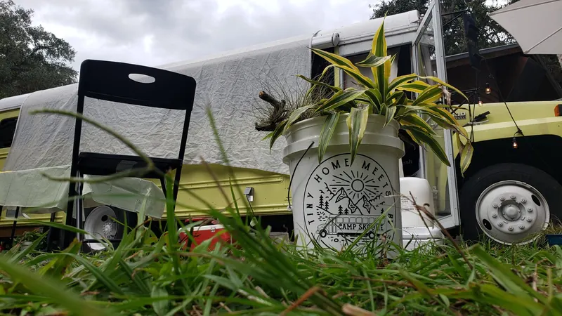 Camp Skoolie bucket planter with the Tiny Home Meets RV badge in front of the yellow bus
